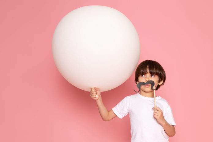 front-view-cute-child-boy-white-t-shirt-holding-white-ball-pink-desk
